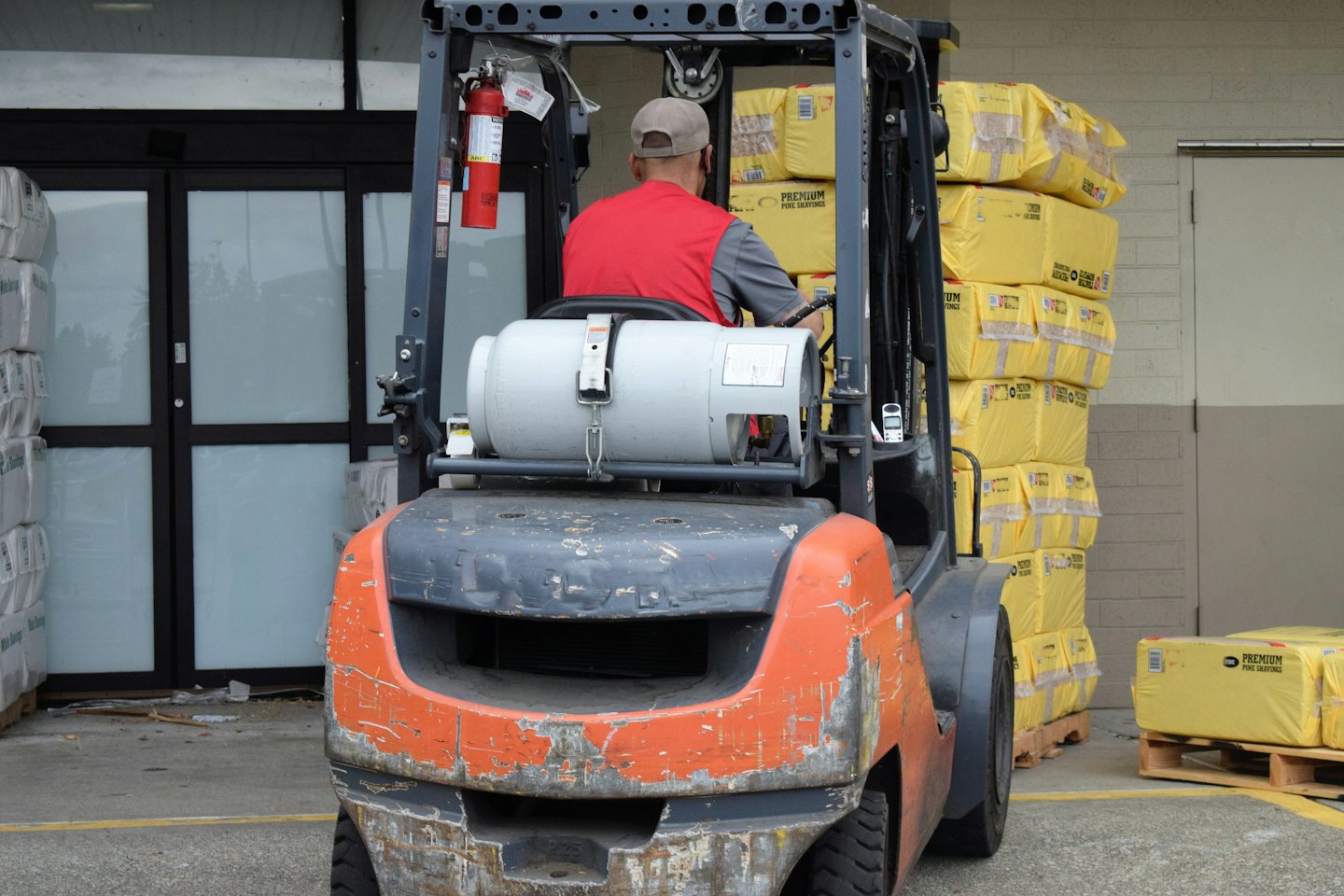 Mitarbeiter fährt orange Gabelstapler mit Inventar im Laderaum.